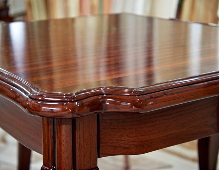 Close-up of a polished wooden table with ornate edges and a rich, dark finish.