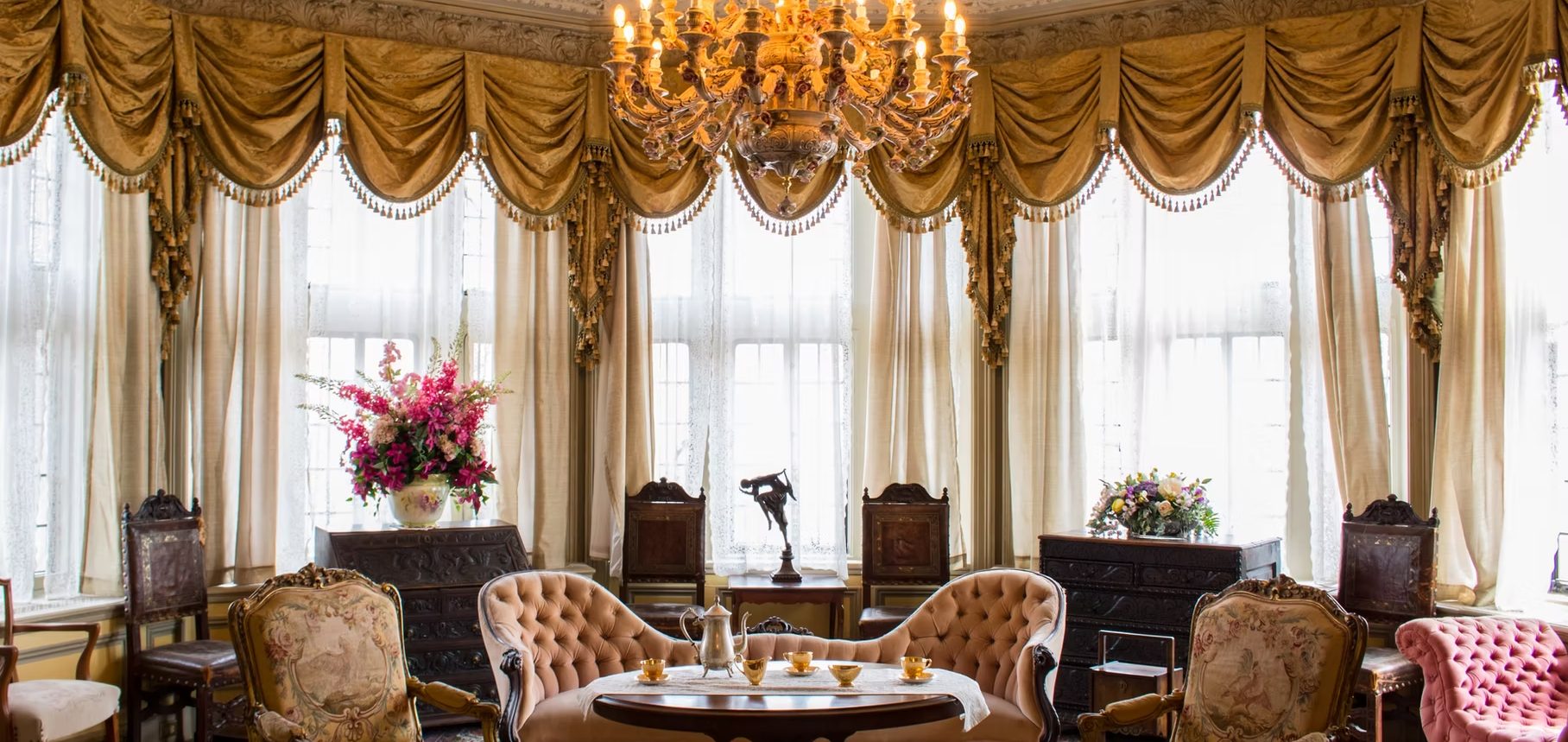 Elegant lounge with ornate drapes, chandelier, and floral arrangements.