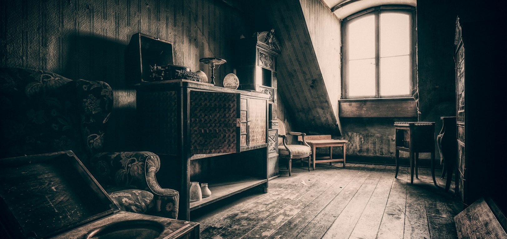 A dimly lit, vintage attic with wooden floors and old furniture.